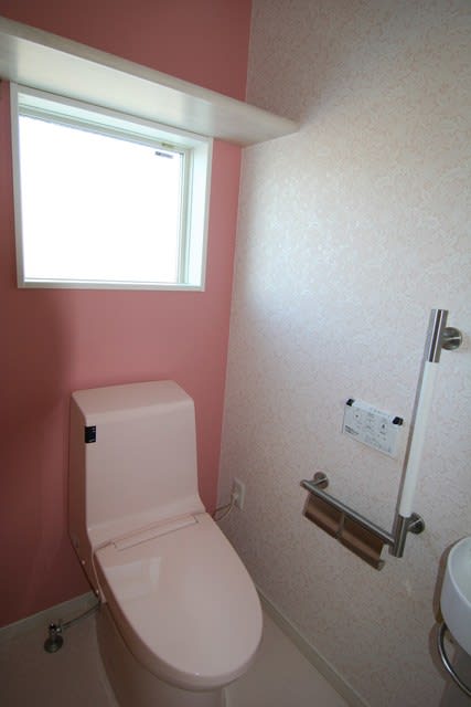 ピンクのアクセントクロスとホワイト花柄レース模様壁紙を使ったトイレ
