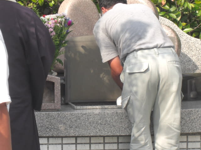 職員さんが共同墓地の蓋を開けて、パウダー状にしたお骨を埋葬しています