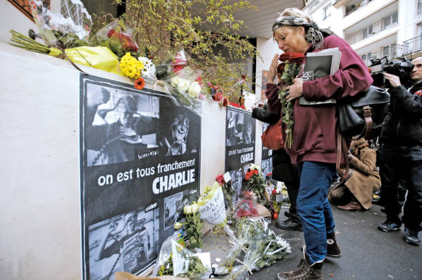 襲撃事件のあった週刊紙シャルリエブドの建物の前に花束をささげる女性＝ＡＰ【２容疑者の潜伏地域捜索　仏紙テロで知人ら７人拘束】