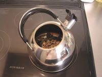 biwa052.jpg: つかんだ茶葉をやかんに入れる