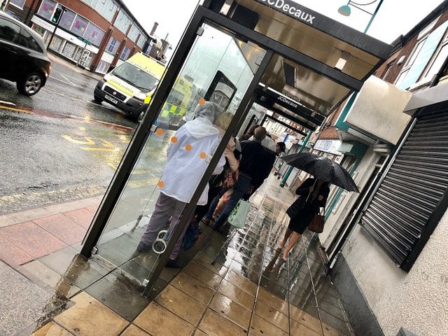 雨の日のバス停 荷物のように抱えられてバスを待つ忠犬 イギリス ストックポート日報 England Daily Stockport